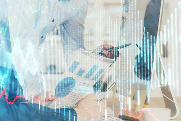 Double exposure of chart with businessman typing on computer in office on background. Concept of hard work.
