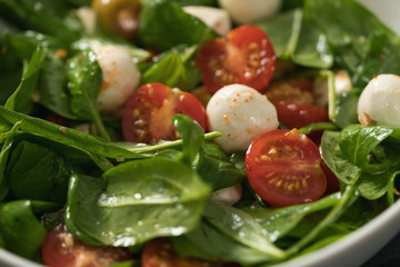 Closeup salad with cherry tomatoes, spinach leaves and mozzarella ball