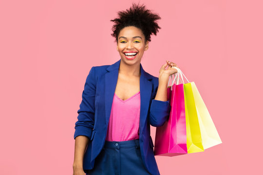 Cheerful black woman with shopping bags at studio