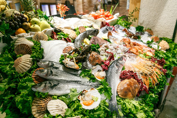 a variety of fresh seafood on a store’s sail. White-headed sea fish, shrimps, crabs, crayfish, mollusks lie on ice