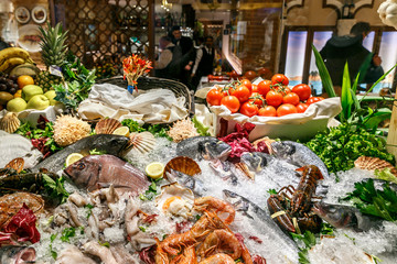 a variety of fresh seafood on a store’s sail. White-headed sea fish, shrimps, crabs, crayfish, mollusks lie on ice