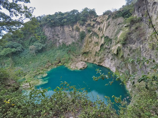 Rear of a woman standing over the rock stretching her hands and enjoying the waterfall, waterfall...