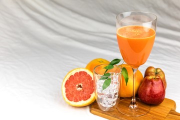 Fresh juice of red grapefruit with apples on white cloth. Diet drink. Homemade juice. Glass with drink.