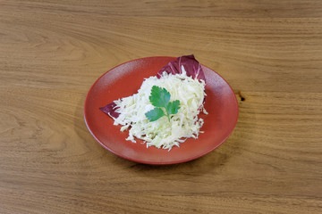 Restaurant food served on a red plate. Fish, cheese, salad, vegetables, sauce.