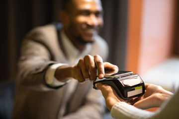 Afro businessman paying with his cellphone at bar