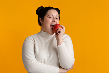 Positive Young Plus Size Girl Eating Red Apple