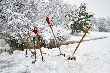 Some snow shovels for snow removal in deep fresh snow with gloves. Snow removal concept. Weather...