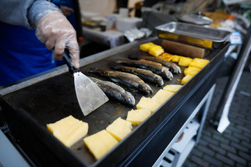 Shallow depth of field (selective focus) image with a man cooking trout fish and polenta on a stove outdoors on a cold day.