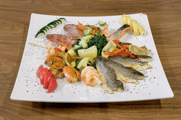 Food on a white plate served on the wooden table, top view.