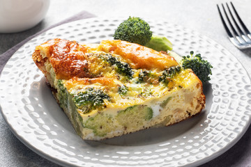 Piece Baked omelet with broccoli on a plate. Concrete table. Healthy diet food dish.