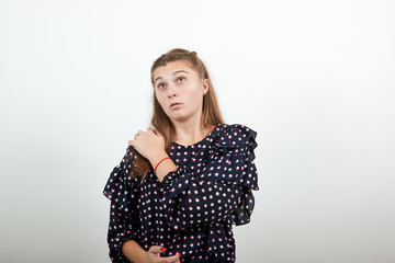 Fair-haired beautiful girl in a black dress with white circles holds her shoulder in pain