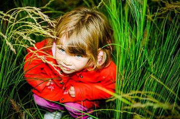 portrait of a scared little girl hidden in the grass