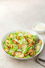 traditional Caesar salad with lettuce, roasted chicken,  croutons and cheese in white bowl, selective focus. copy space