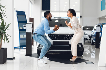 Joyful Family Couple Celebrating Buying New Car In Automobile Dealership