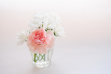 ピンクのカーネーションと白い菊の小さなブーケ 右にコピースペース 白背景
