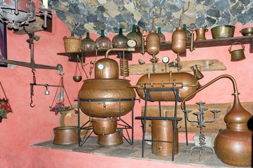 An old moonshine still stands in a cellar with pink walls.