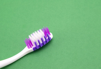 White-violet toothbrush. On a green background. Head with bristles.