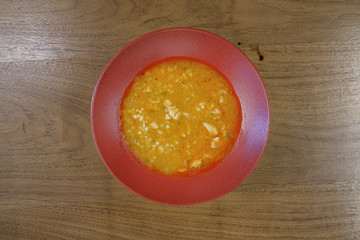 Restaurant food served on a red plate. Fish, cheese, salad, vegetables, sauce.