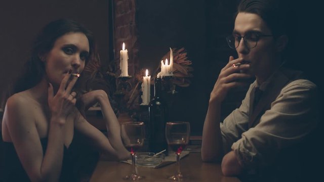 Couple at romantic dinner with candles and wine, looking in camera, shallow depth of field, slow motion