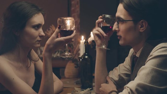 Couple at romantic dinner with candles and wine, shallow depth of field, slow motion