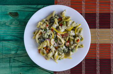 pasta with vegetables and cheese on a white plate on a color background, view from above home-cooked food
