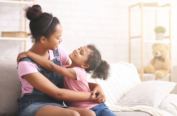Cheerful african sisters hugging at home, empty space