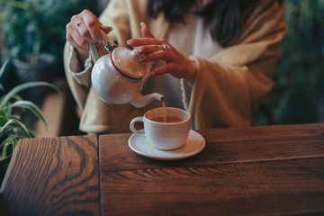 Female hands pouring tea into cup - 321809225