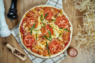 Homemade baked pizza margherita with tomatoes and mozzarella, red sauce wooden background. Close up view, flat lay. Traditional italian cuisine