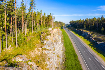 Obraz premium Karelia. Russia. The road goes beyond the horizon. Northern nature. Pine trees grow on the rocks. The highway is empty. Rest begins. Feeling of spaciousness. Fresh air.