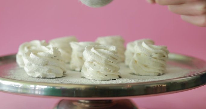 Sprinkling powder on the sweet dessert cakes, pink background