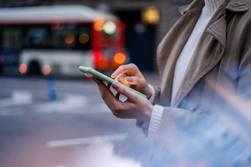 Closeup photo of female hands with smartphone. Night street on background