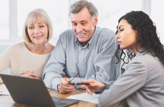 Serious Latina Worker Offering Tour To Happy Elderly Couple