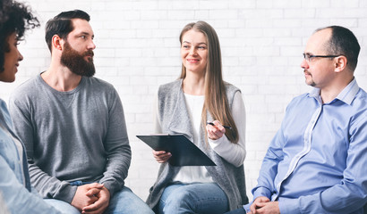 Psychotherapist talking with patients during group therapy session and taking notes