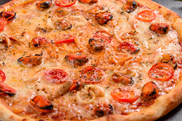 Tasty sliced pizza with seafood and tomato on a concrete background