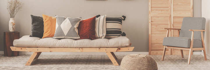 Vintage armchair with chequered pattern next to comfortable beige sofa with pillows in beautiful...