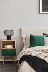 Beige and emerald bedroom design with modern lamp on wooden nightstand table
