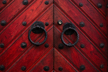 Authentic red wooden front door of an old european house. Closeup photo of the decorated door`s...