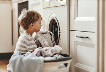 happy  householder child boy in laundry   with washing machine.