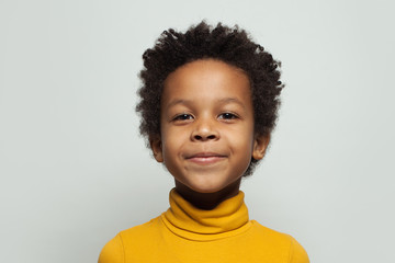 Little black kid boy smiling on white background, close up portrait