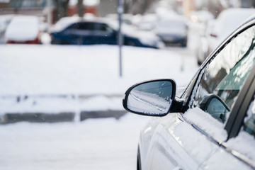 Car mirror in the snow. The concept of winter conditions on the road, ice and bad weather for driving vehicles.