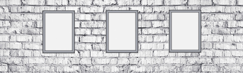 Blank photo frames on rough light gray brick wall