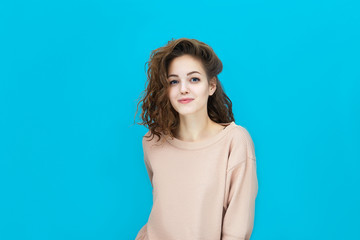 Portrait of a young beautiful woman wearing sweatshirt looking at you coquettishly isolated over blue background