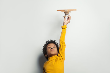 Little black child boy playing plane model on white background