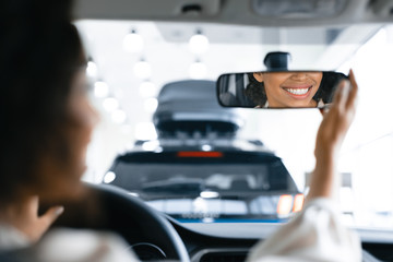 Unrecognizable Woman In Driver's Seat Checking Mirrors In Dealership Showroom