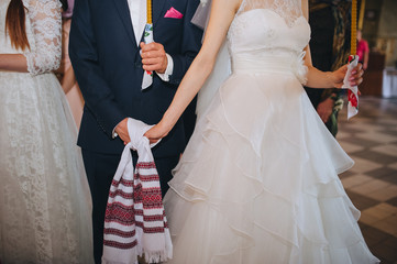 Hands of the newlyweds close-up, tied with a rushnyk at the ceremony. Wedding Ukrainian traditions. Photography, concept.