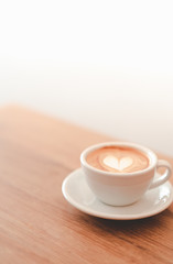 a cup of hot latte coffee on brown wood, heart shape latte art, coffee lover concept, vintage tone