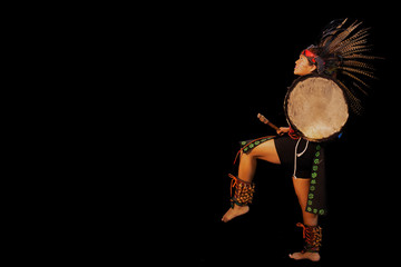 young woman Teotihuacana, Xicalanca - Toltec in black background, with traditional dress dance with a trappings with feathers and drum