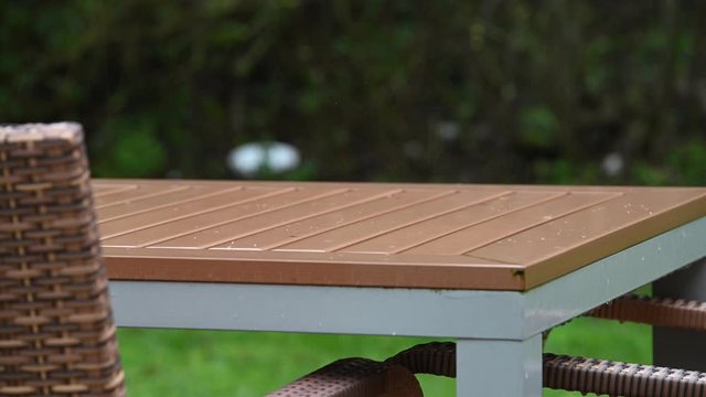 Regen prasselt auf einen Gartentisch