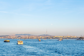 Many passenger ferry boats on the water in Istanbul with Üsküdar district in the background and Camlica tower. Trasnportation in Istanbul, Turkey.