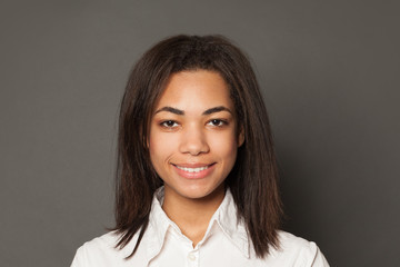 Fototapeta premium Young confident black woman student smiling on gray background, face close up